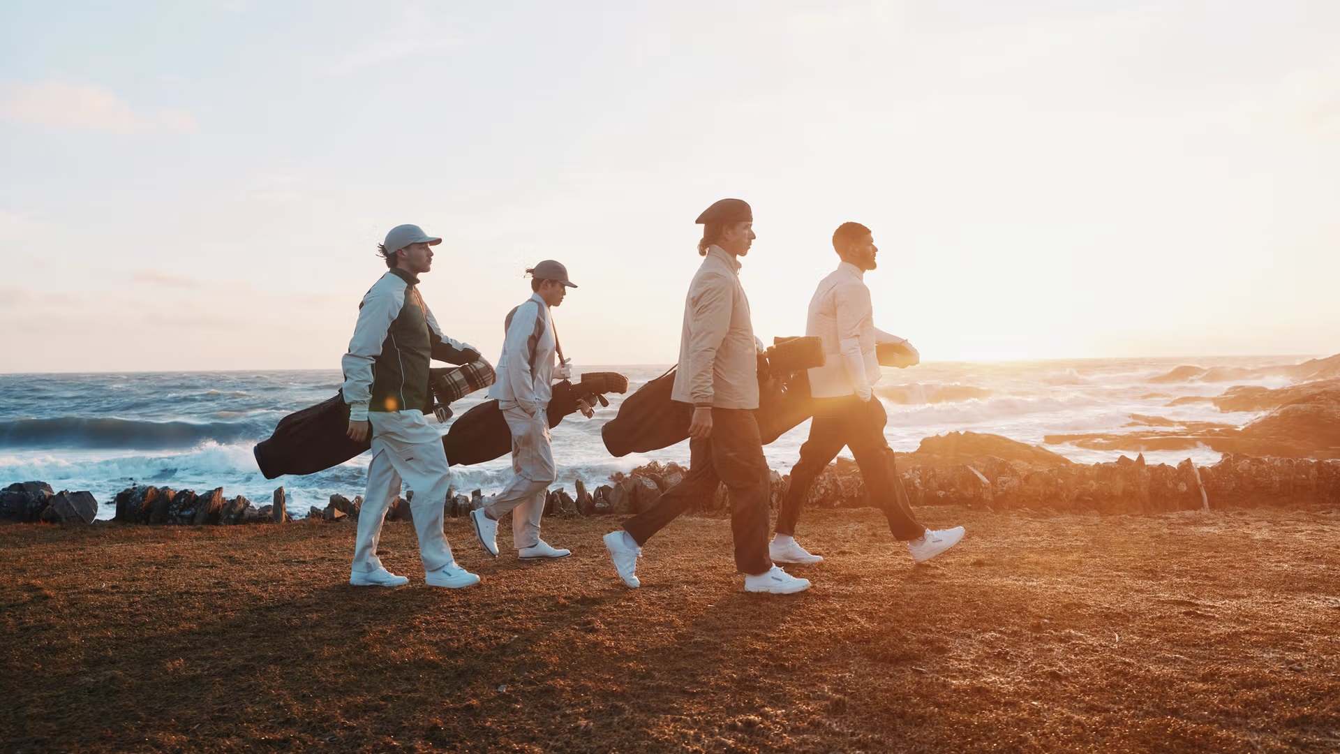 Four golfers walking at golden hour by the ocean